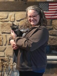 A woman holding a black cat in her arms.