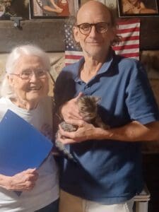 An older couple holding a cat and smiling.