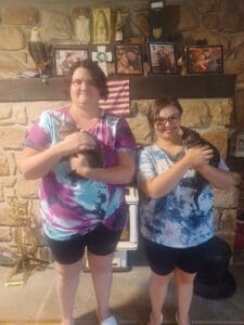 Two women holding a cat in their hands.